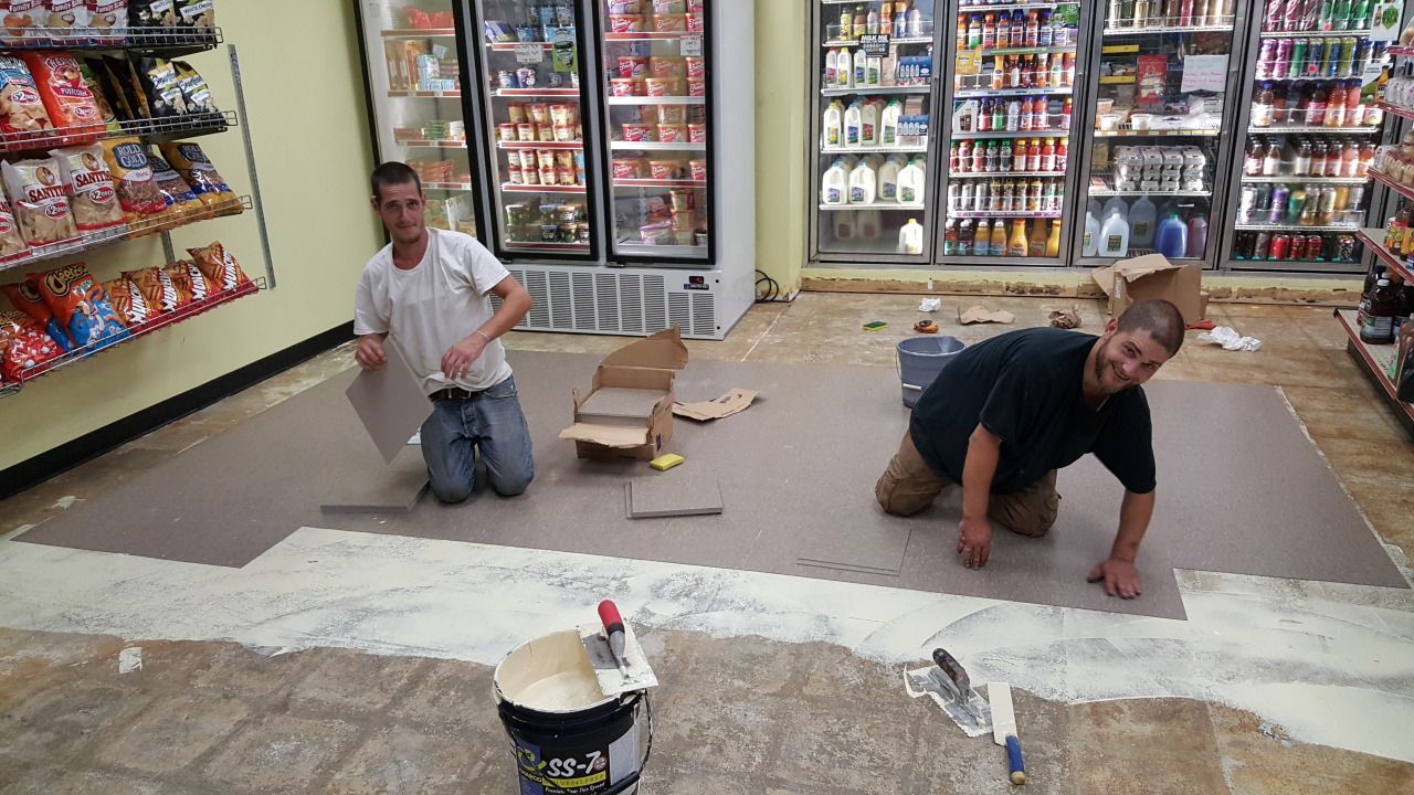 Two men are kneeling on the floor in a store.