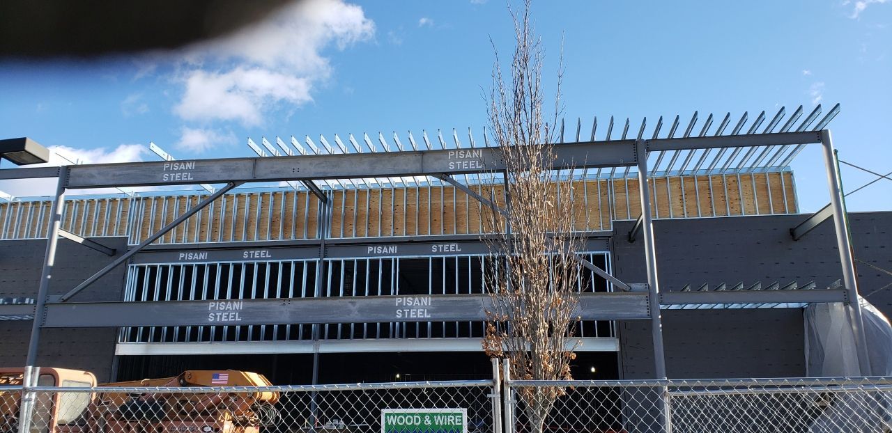 A building under construction is behind a chain link fence.