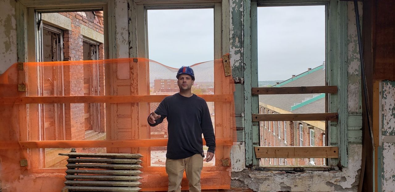 A man is standing in front of a window in a building under construction.