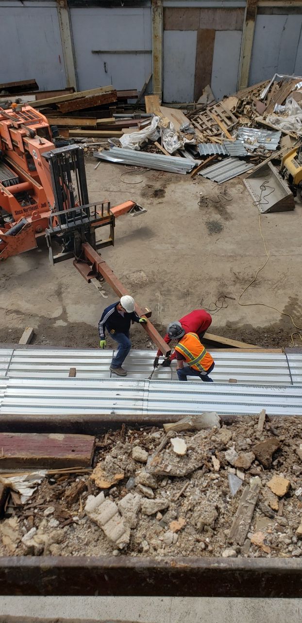 A group of construction workers are working on a metal roof.