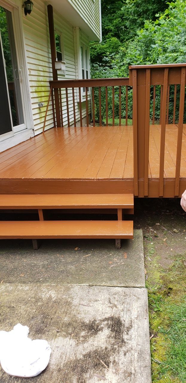 A wooden deck with stairs is sitting on the side of a house.