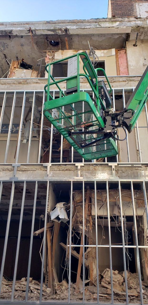 A green crane is being used to demolish a building.
