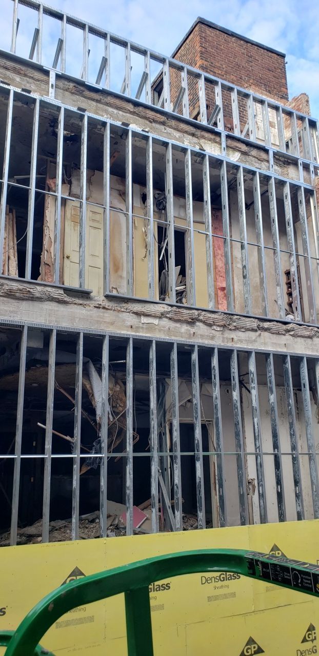 A building under construction with a green tractor in the foreground.