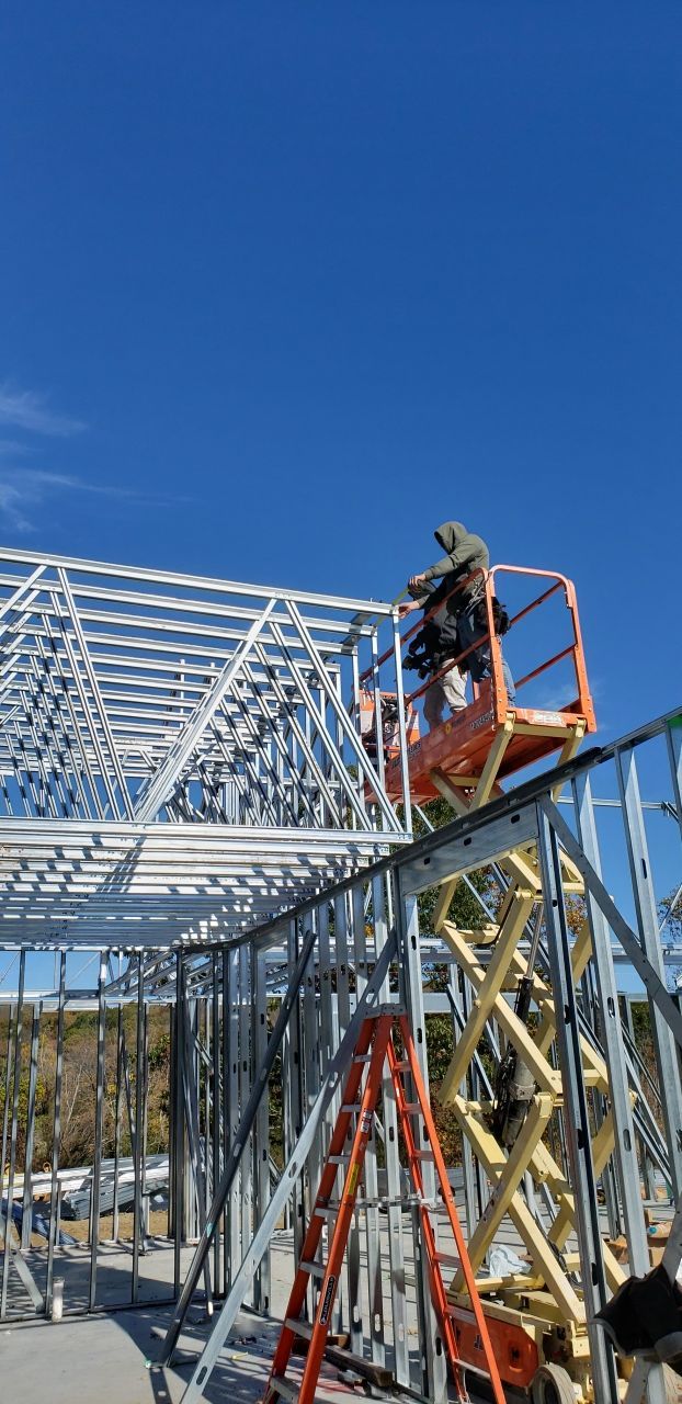 A man is standing on a lift on top of a building under construction.