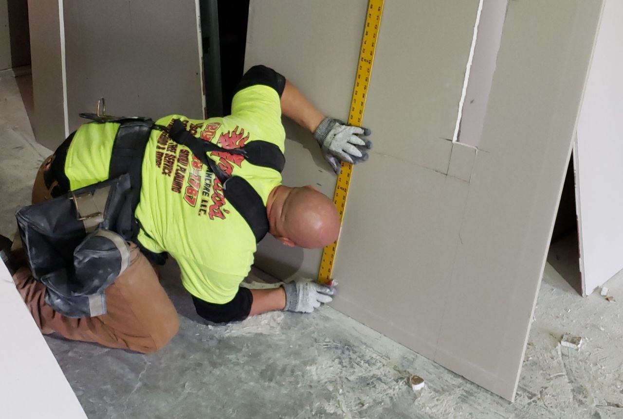 A man is measuring a wall with a tape measure.