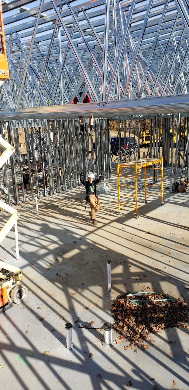 A man is standing on a scaffolding in a building under construction.