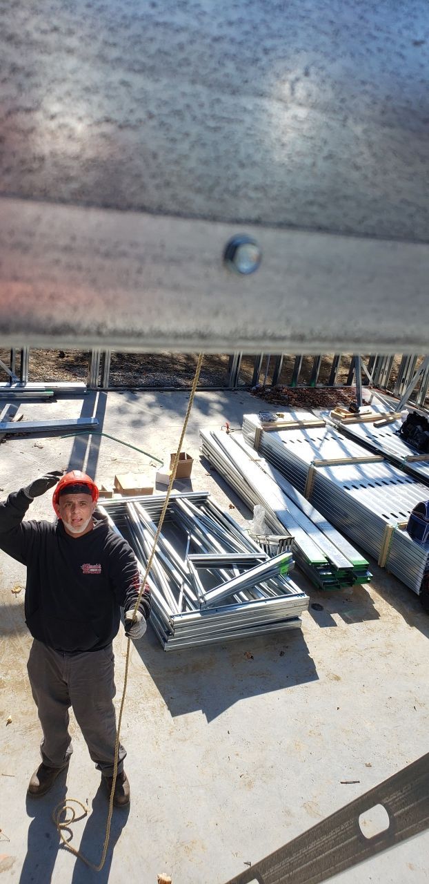 A man in a hard hat is standing in front of a pile of metal.