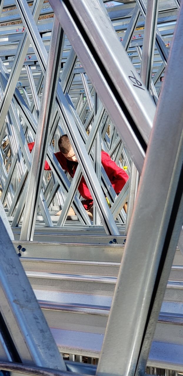 A man in a red shirt is working on a metal structure.