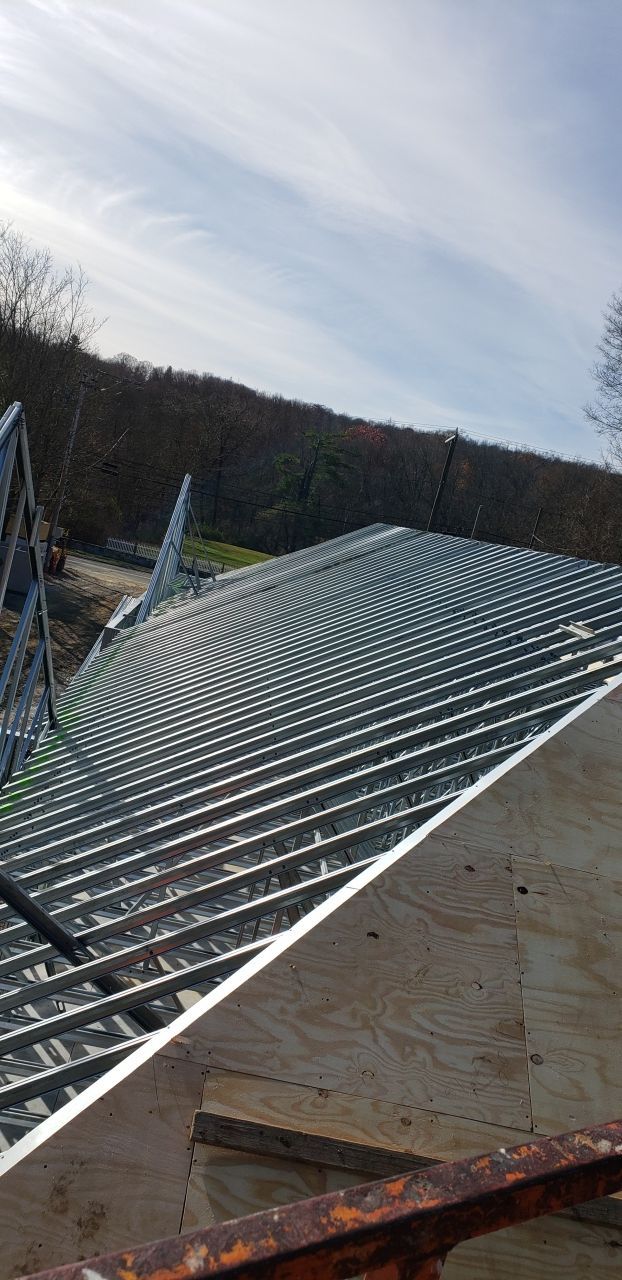A metal roof is being built on top of a concrete floor.