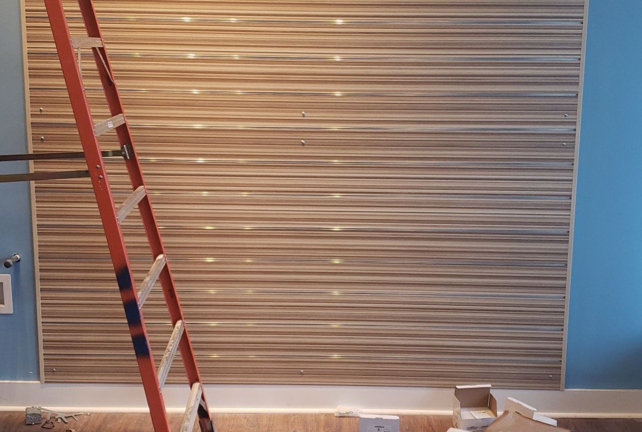 A ladder is sitting in front of a wooden wall.