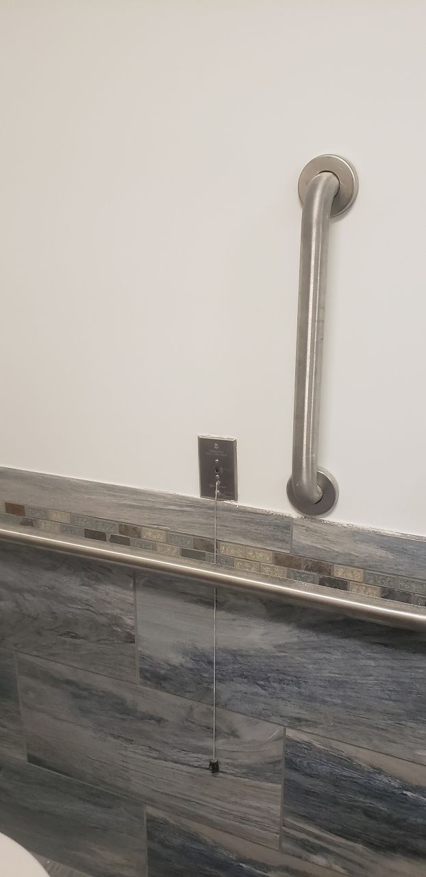A bathroom with a stainless steel grab bar on the wall.
