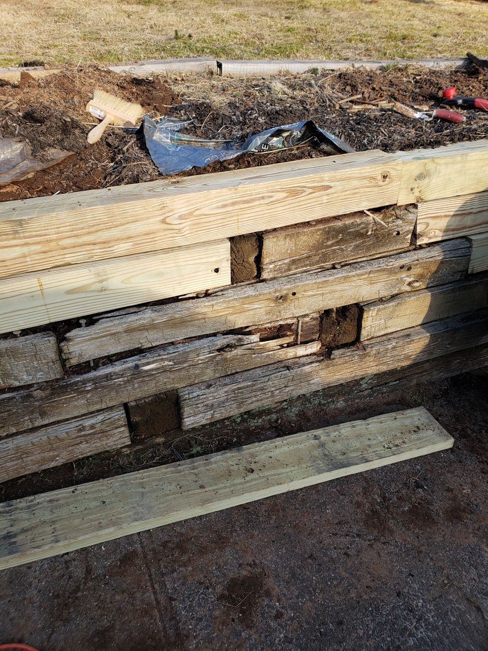 A wooden retaining wall is being built in a garden.