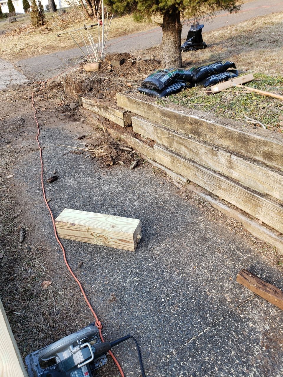 A saw is sitting on the ground next to a wooden wall.