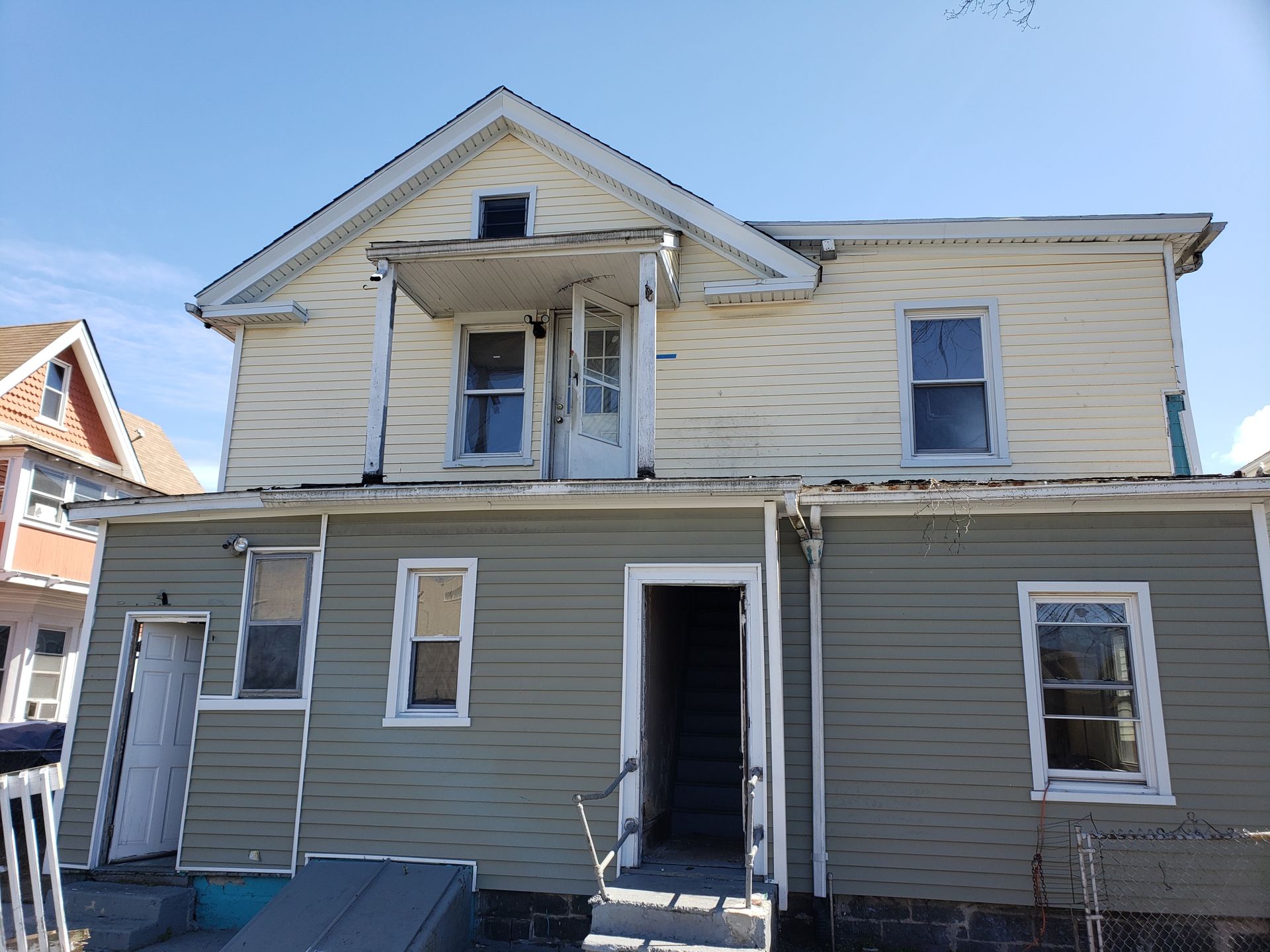 A white house with a green siding and a white door.