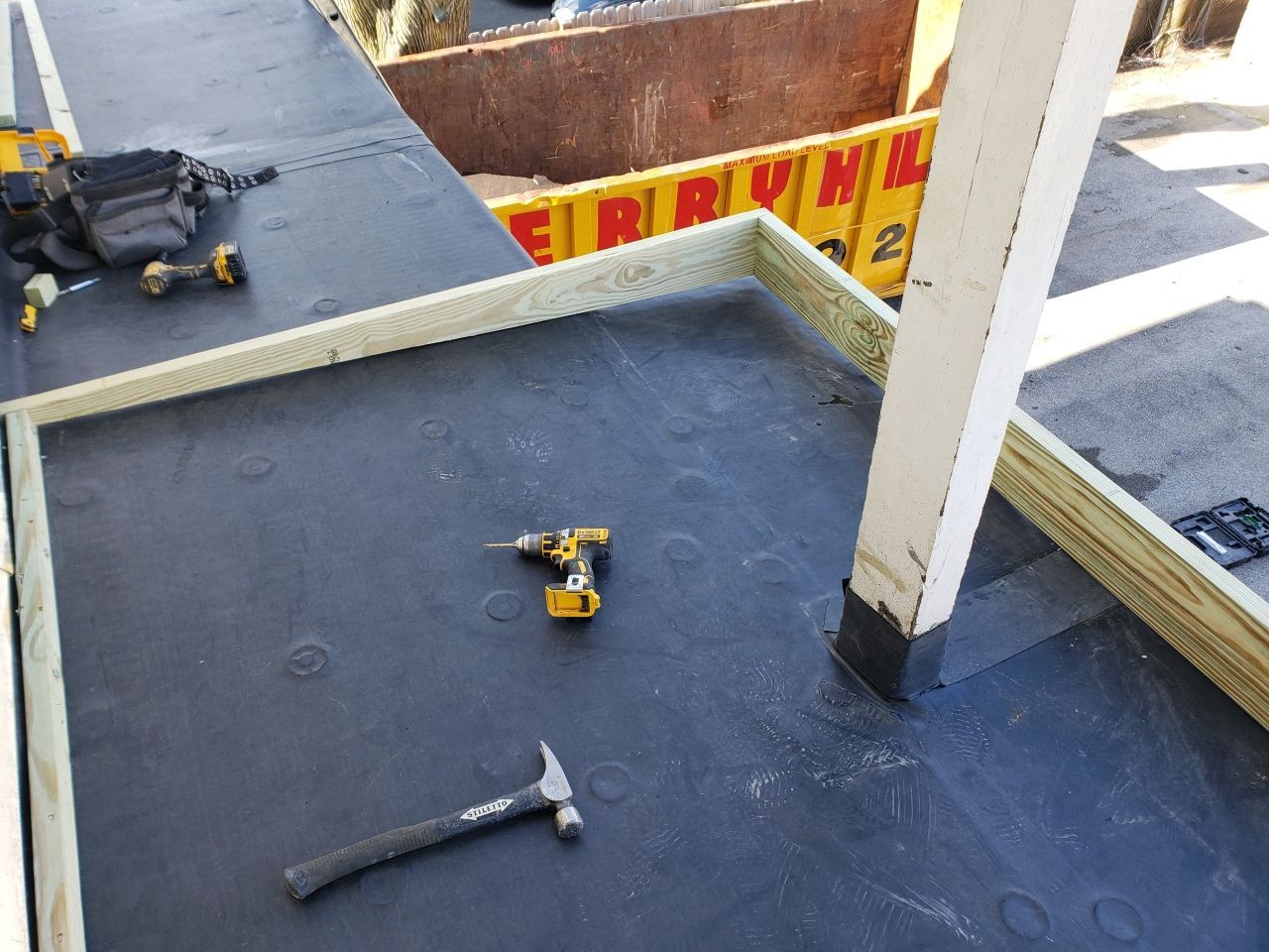 A hammer and a drill are on the floor of a building under construction.