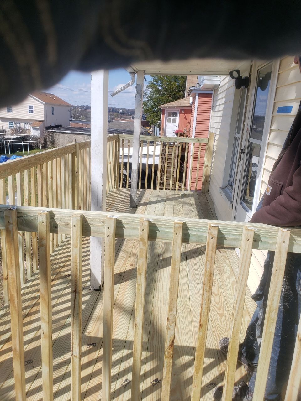 A person is standing on a deck behind a wooden railing.