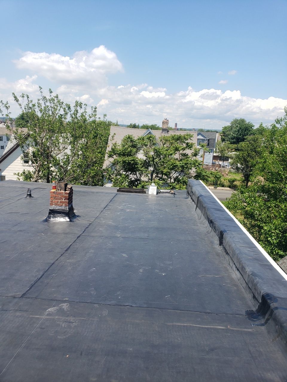 A roof with a chimney on it and trees in the background