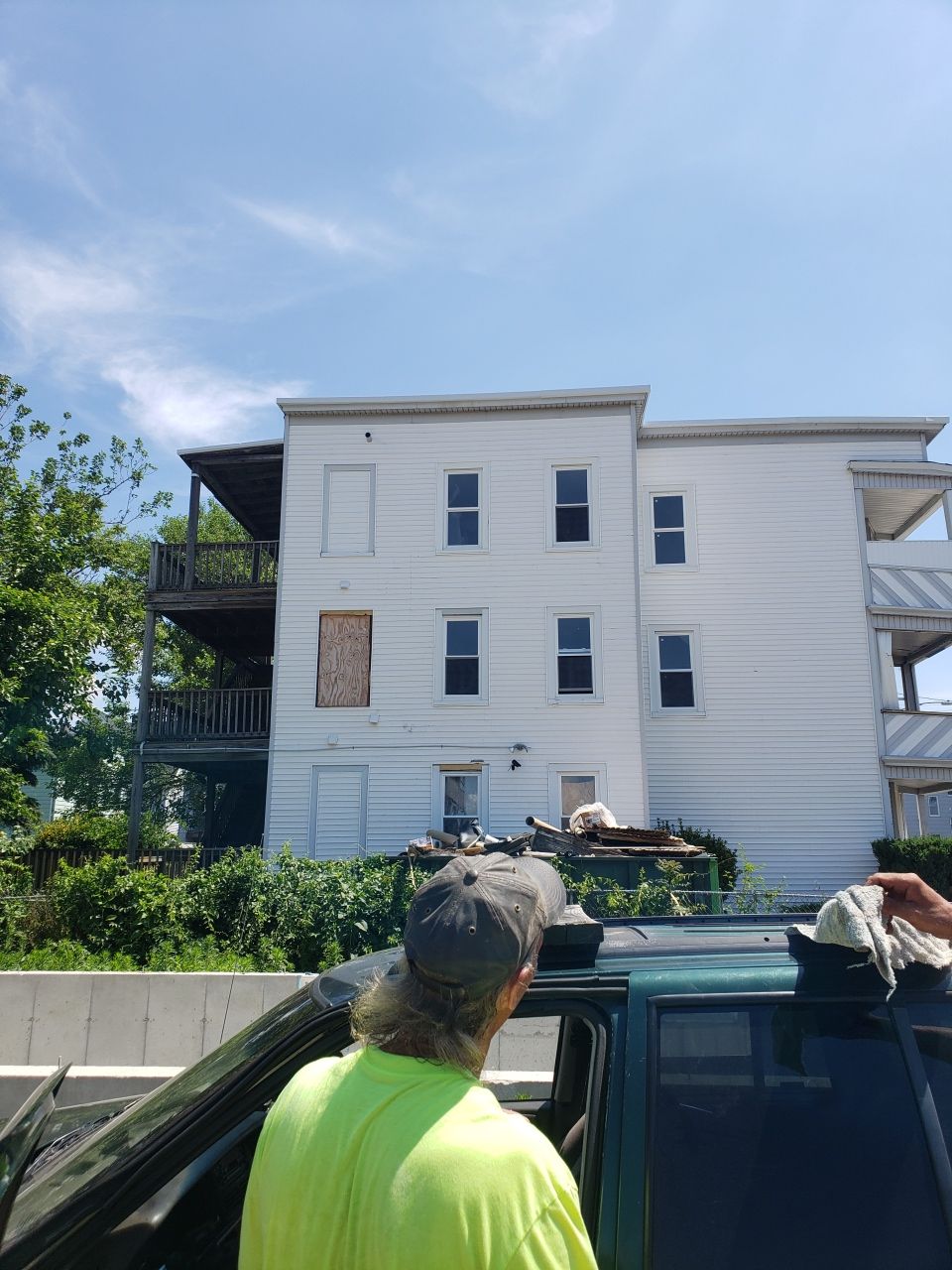 A man in a yellow shirt is standing in front of a white building.