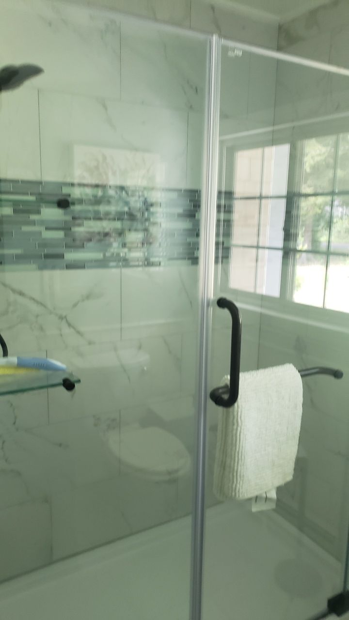 A bathroom with a glass shower door and a toilet.