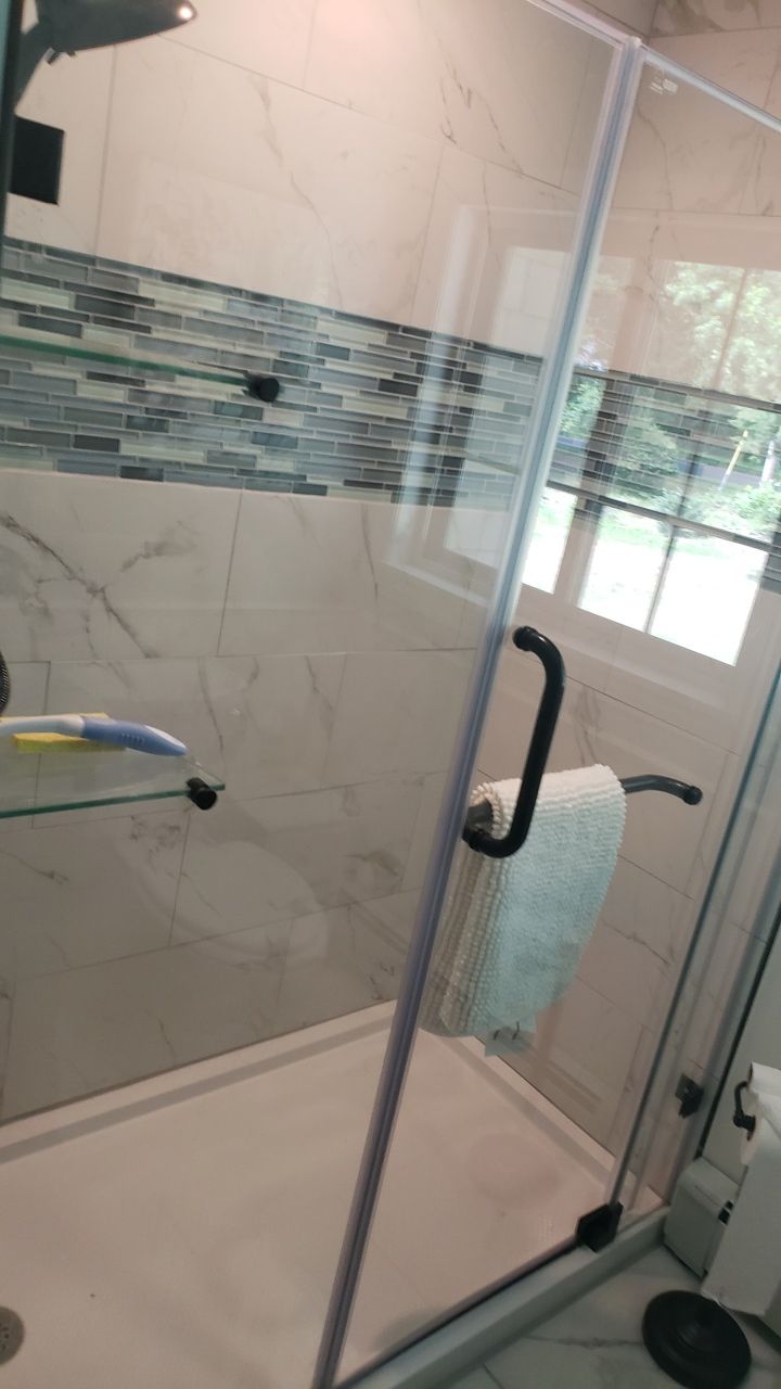 A bathroom with a walk in shower with a glass door.