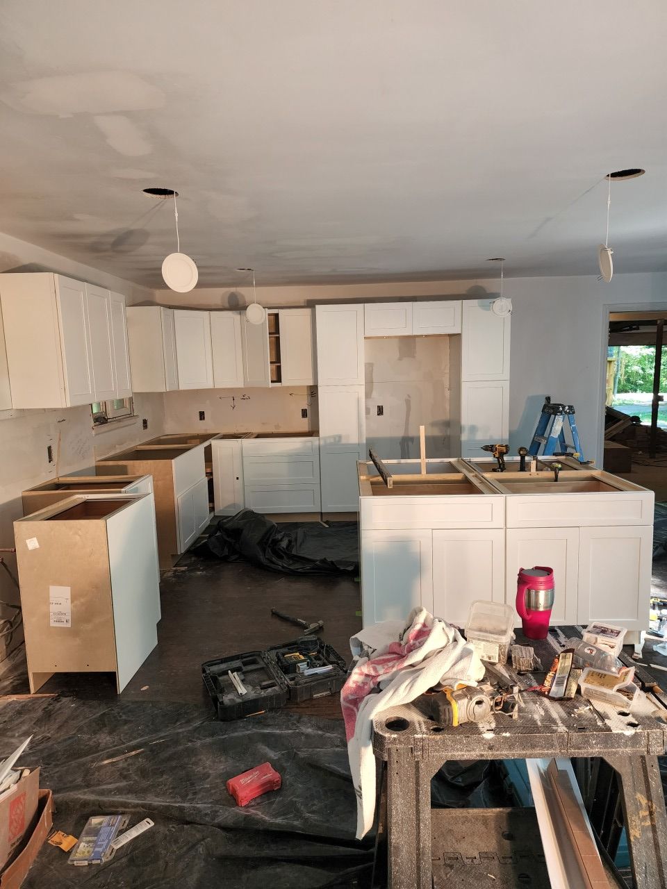 A kitchen is being remodeled with white cabinets and a sink.