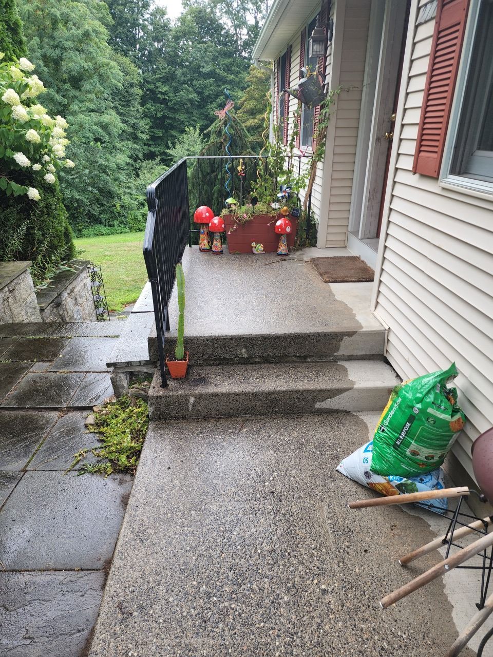 A house with a porch and stairs and a bag of dirt on the sidewalk