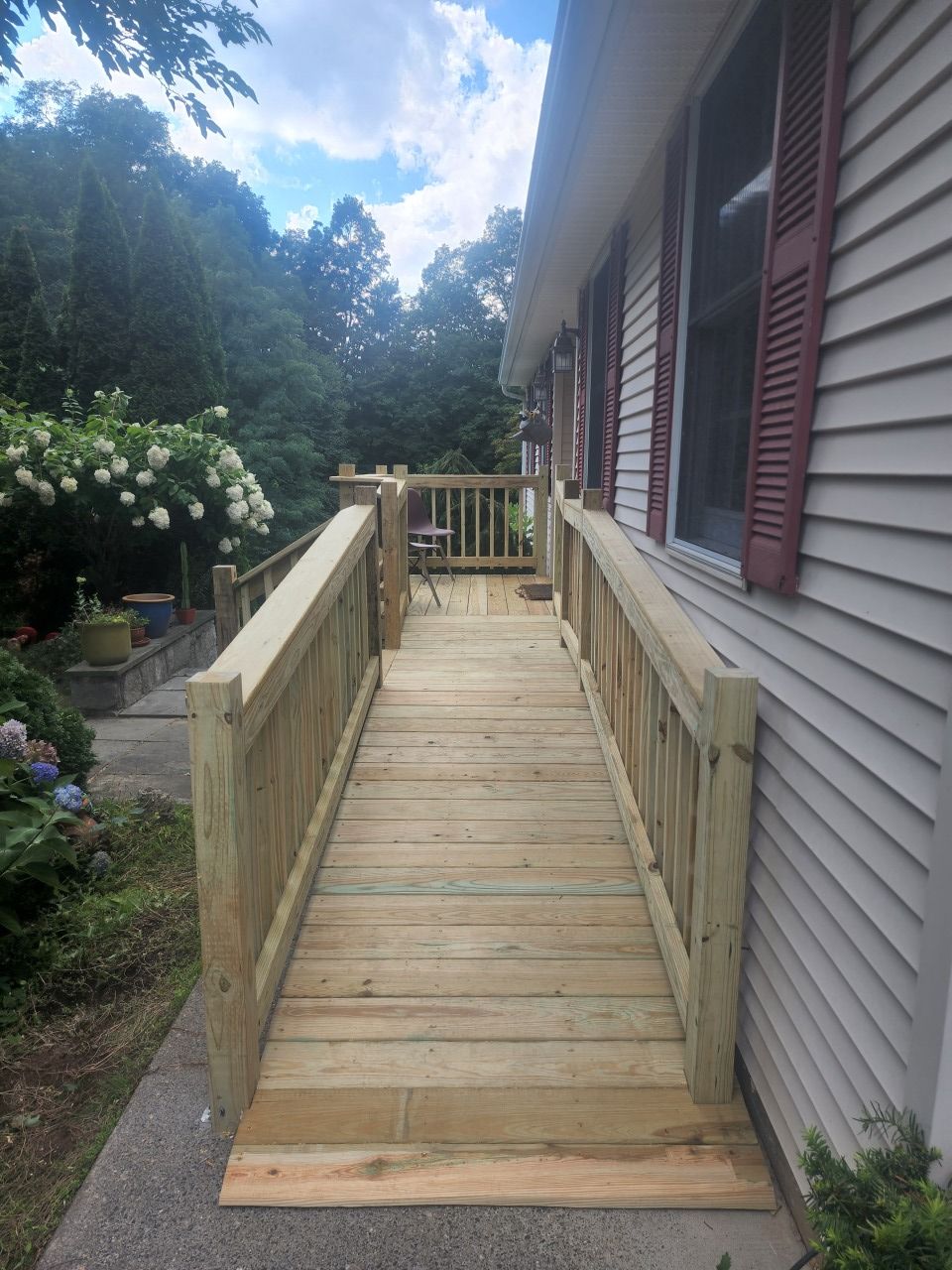 A wooden ramp leading to a deck on the side of a house.