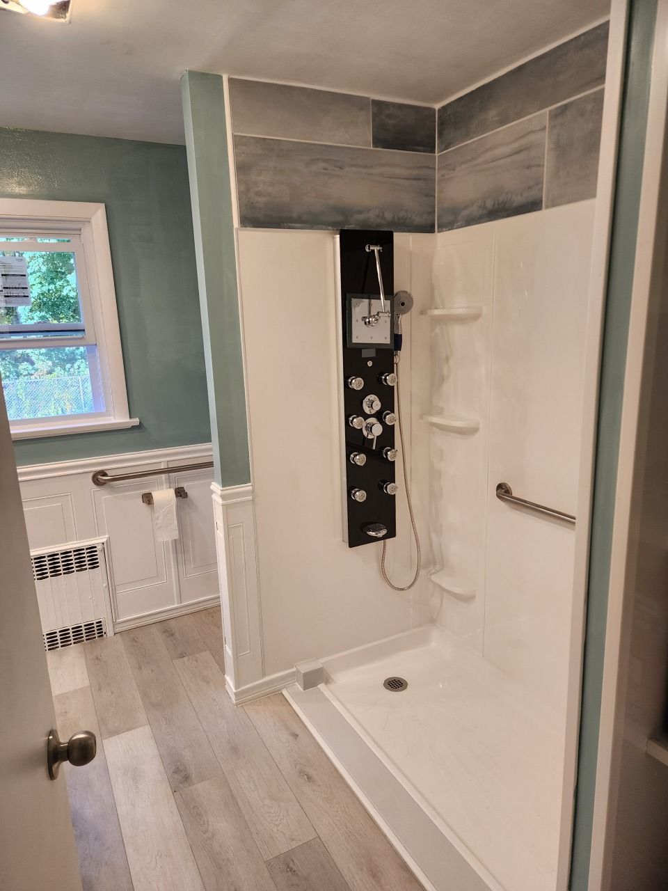 A bathroom with a walk in shower and a window.