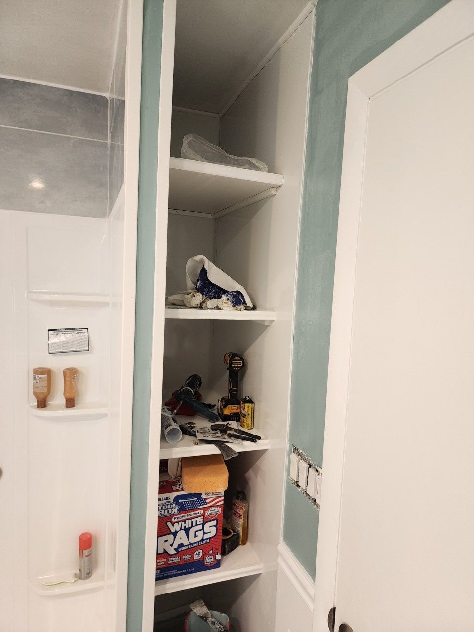 A bathroom with a shelf filled with various items and a box of pabst beer.