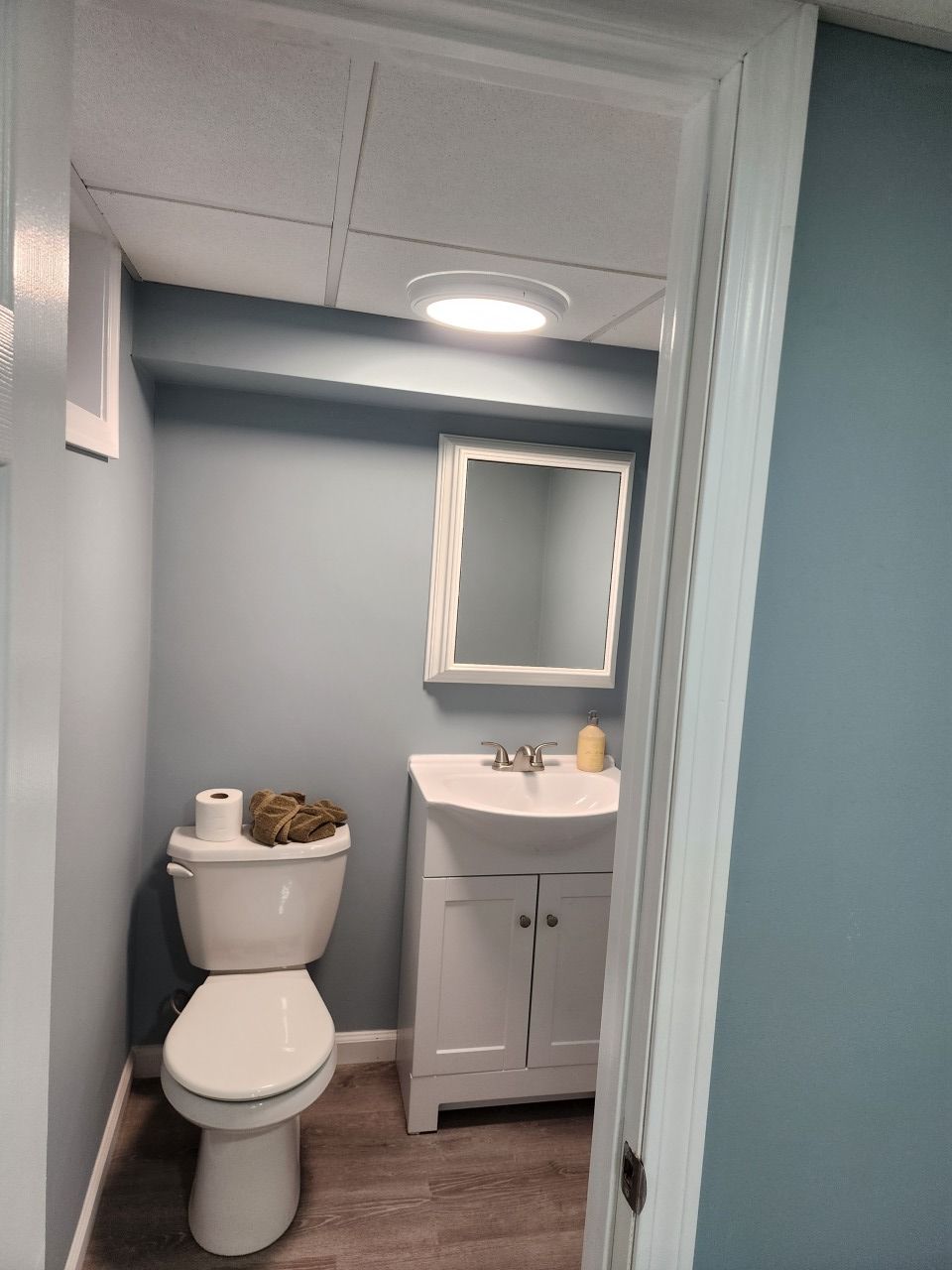 A bathroom with a toilet , sink and mirror.