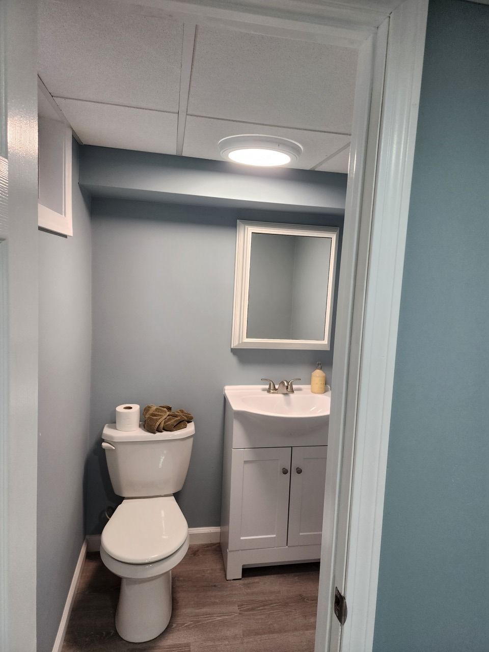 A bathroom with a toilet , sink and mirror.