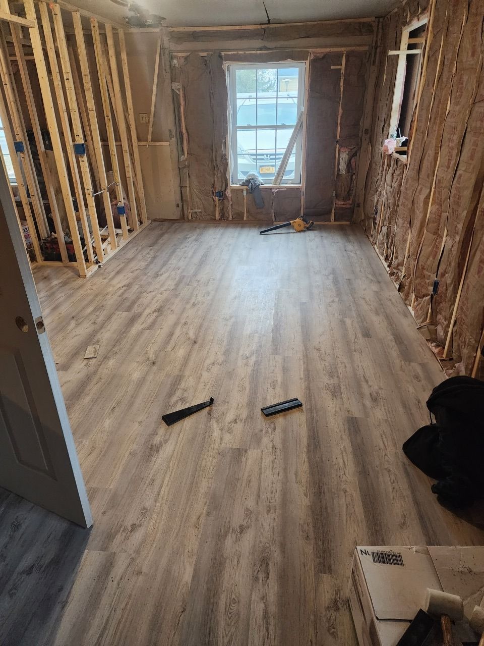 A room with wooden floors and a window in a house under construction.