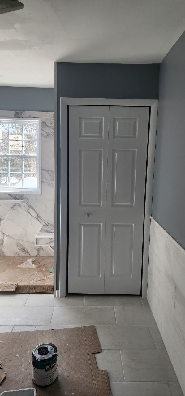 A white door is sitting in a room next to a window.