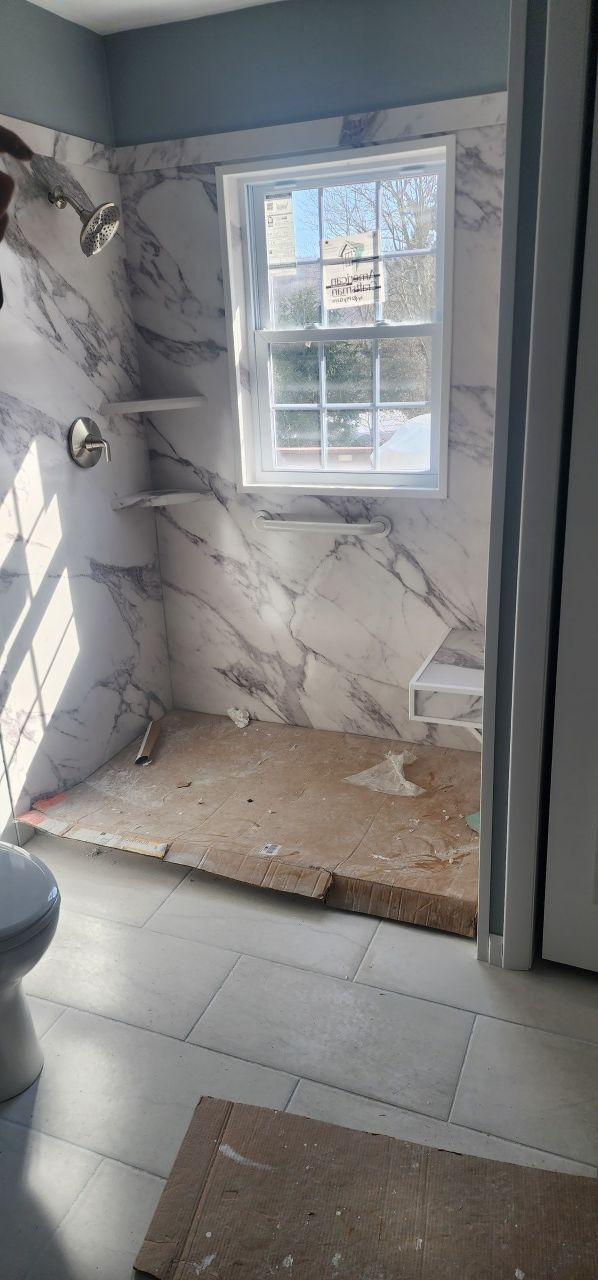 A bathroom with a toilet , shower , and window.