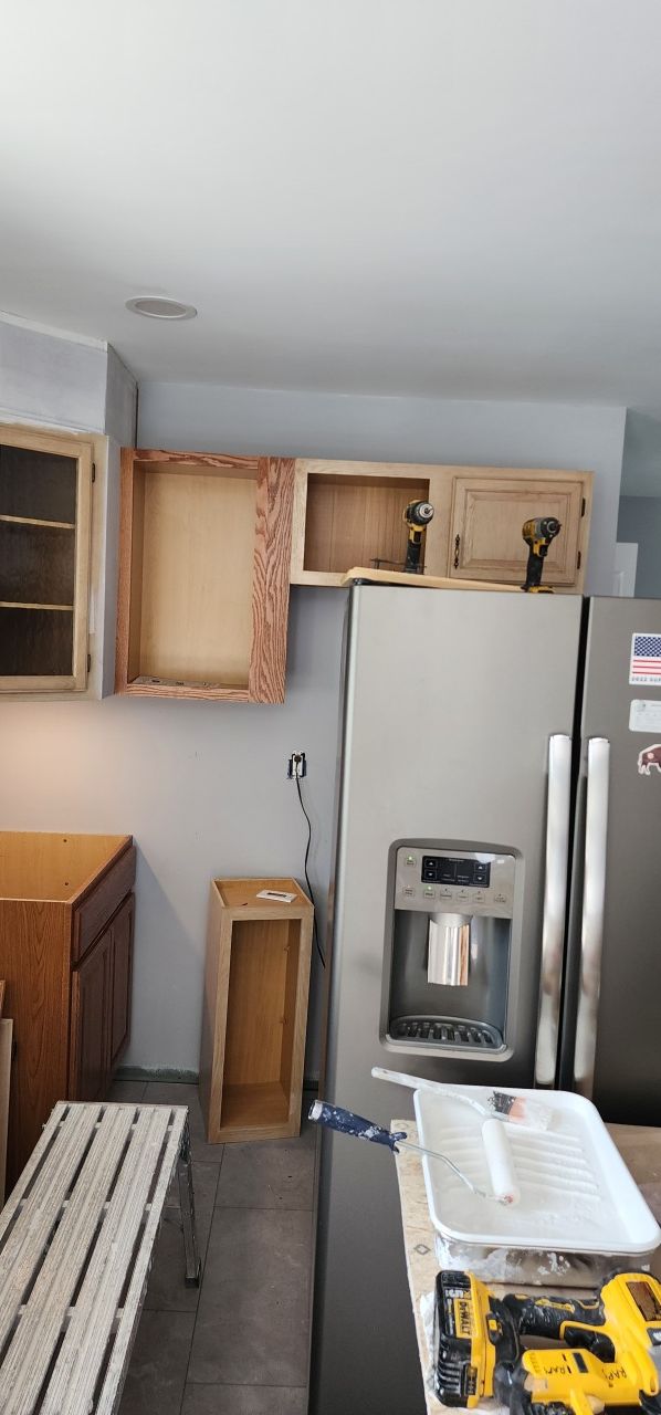 A kitchen with a refrigerator , cabinets , and a table.