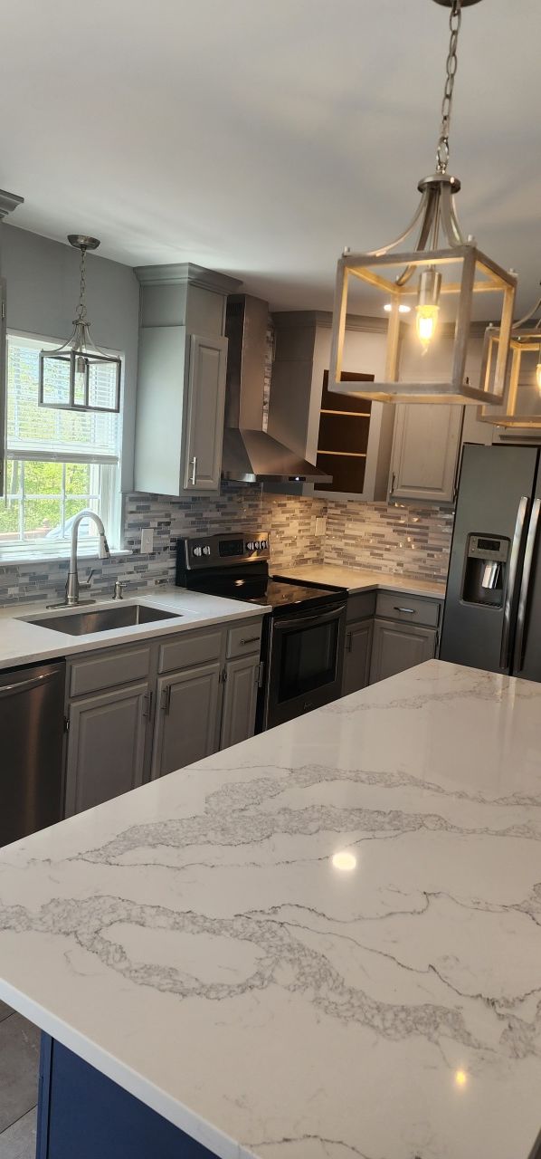 A kitchen with a large island , sink , stove , refrigerator and dishwasher.