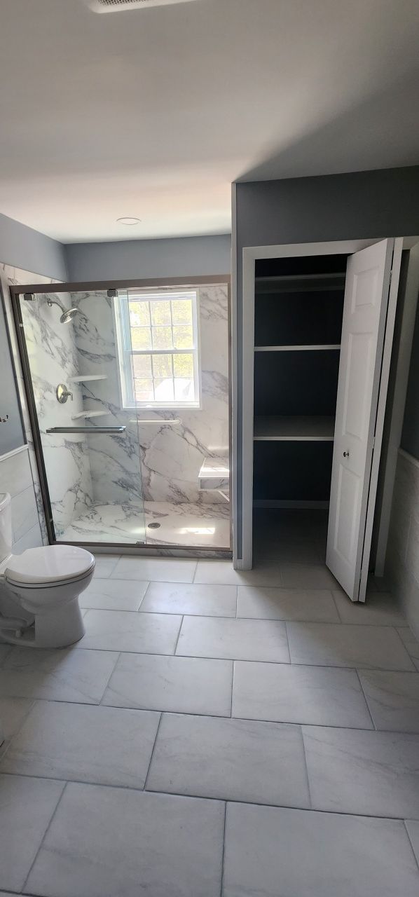 A bathroom with a toilet , shower , and closet.