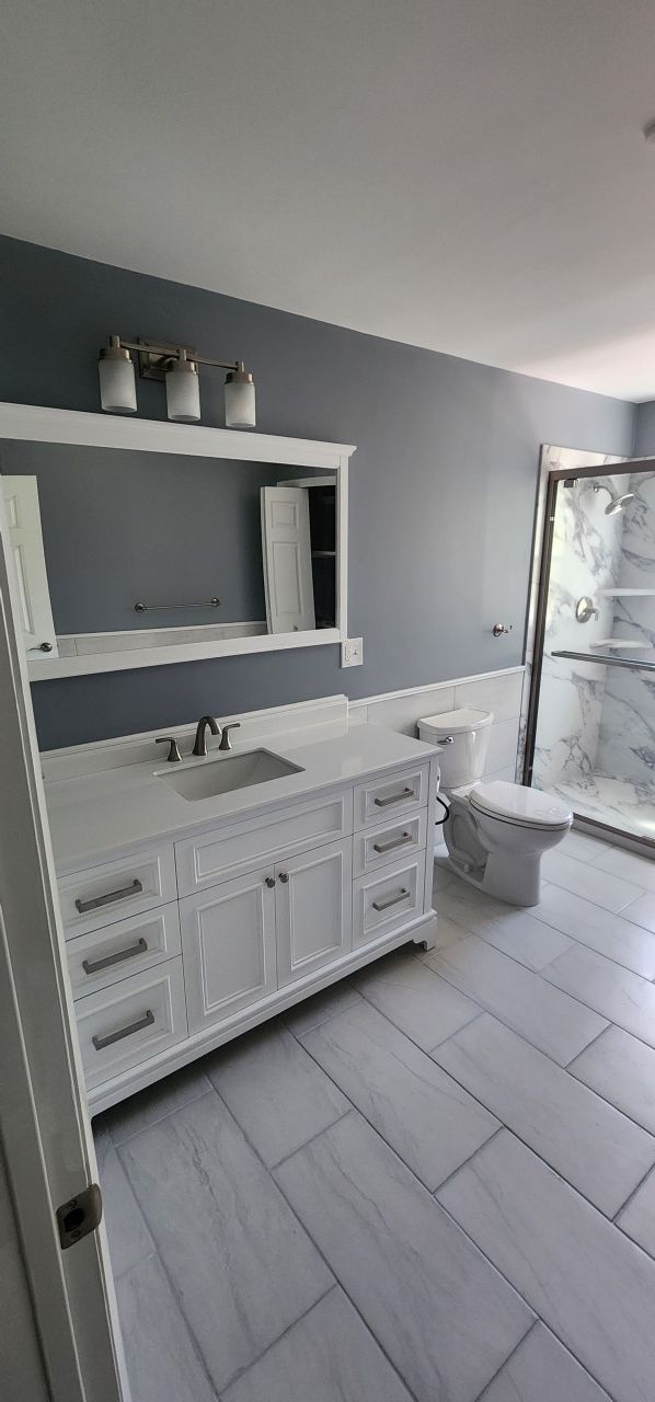A bathroom with a sink , toilet , mirror and shower.