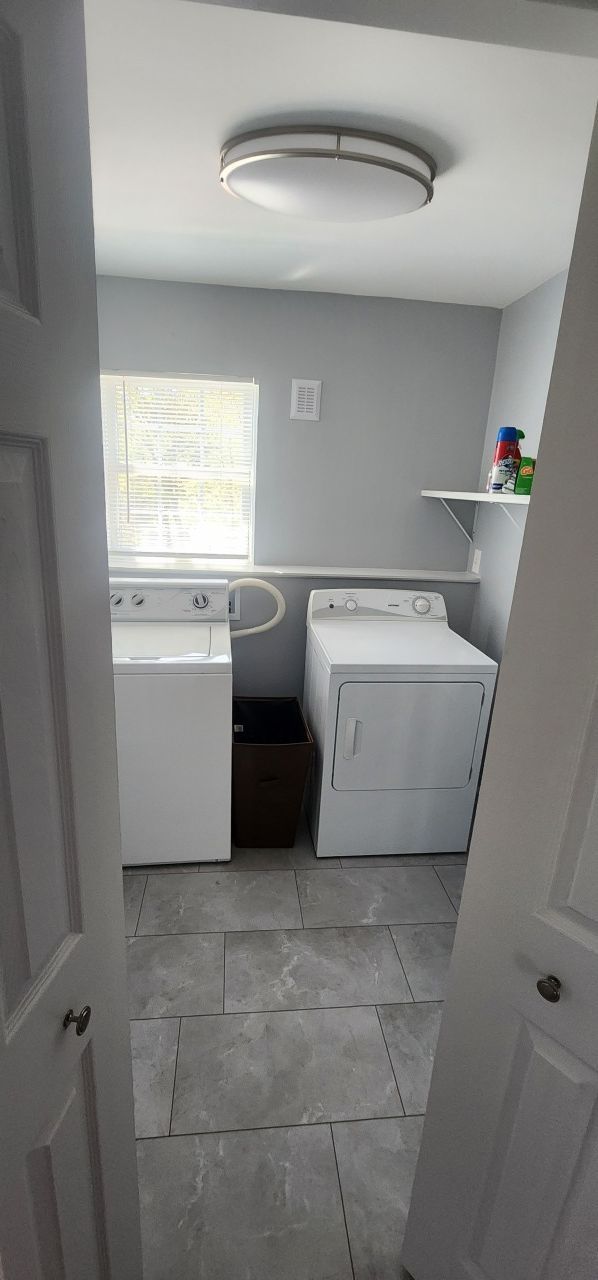 A laundry room with a washer and dryer and a window.