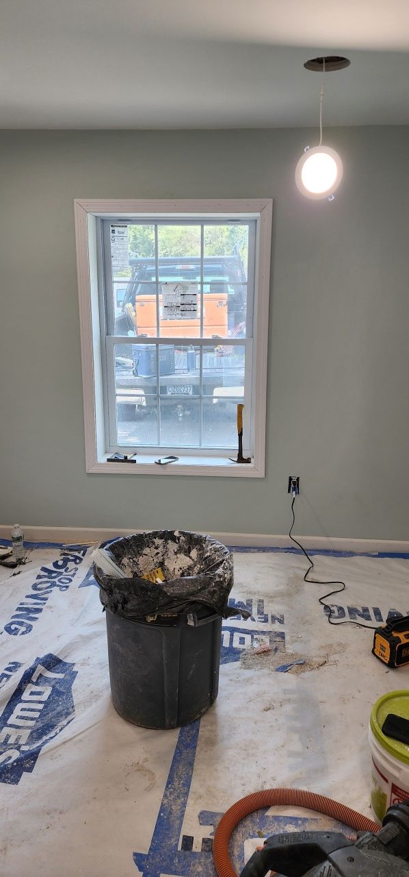 A room with a window and a trash can on the floor.