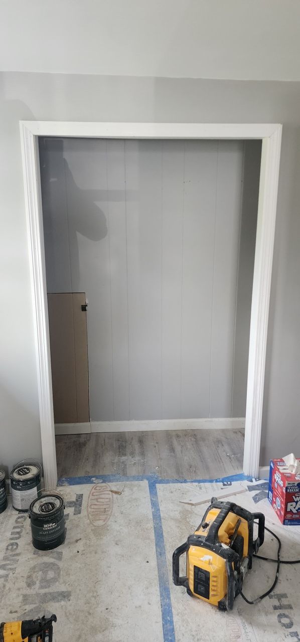 A closet is being painted in a room with tools on the floor.