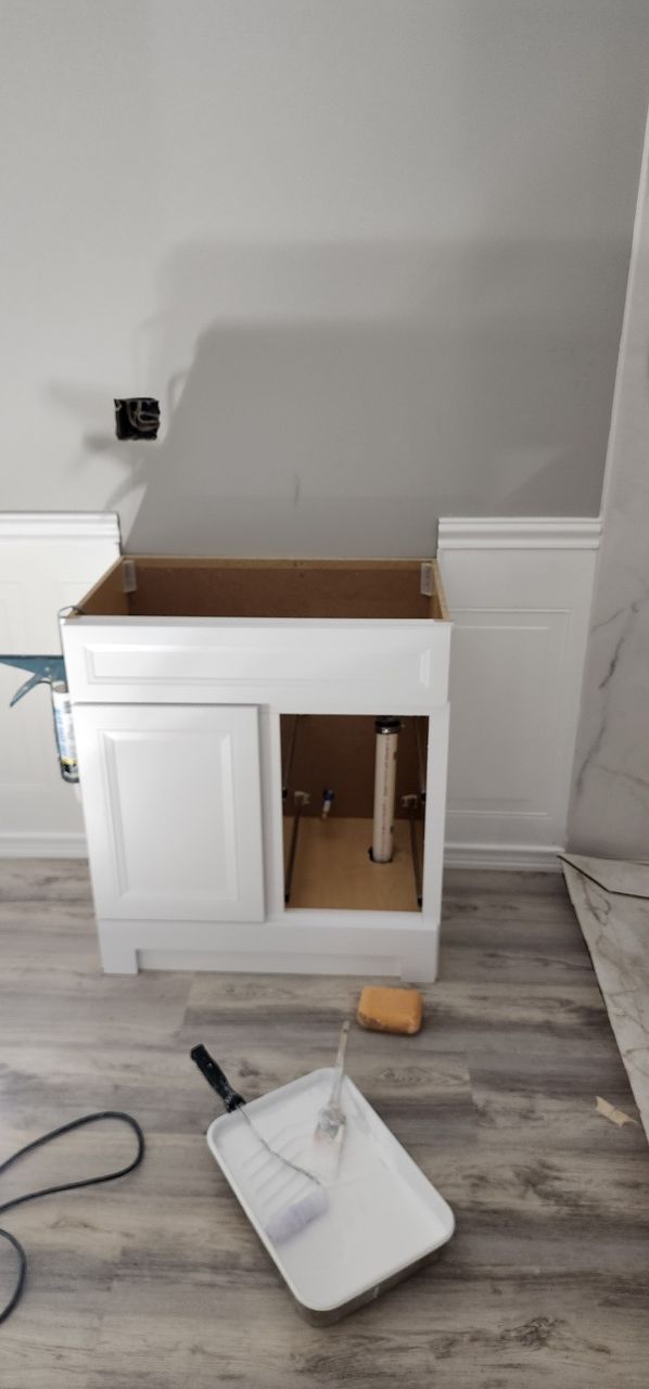 A white vanity is sitting on a wooden floor in a room.