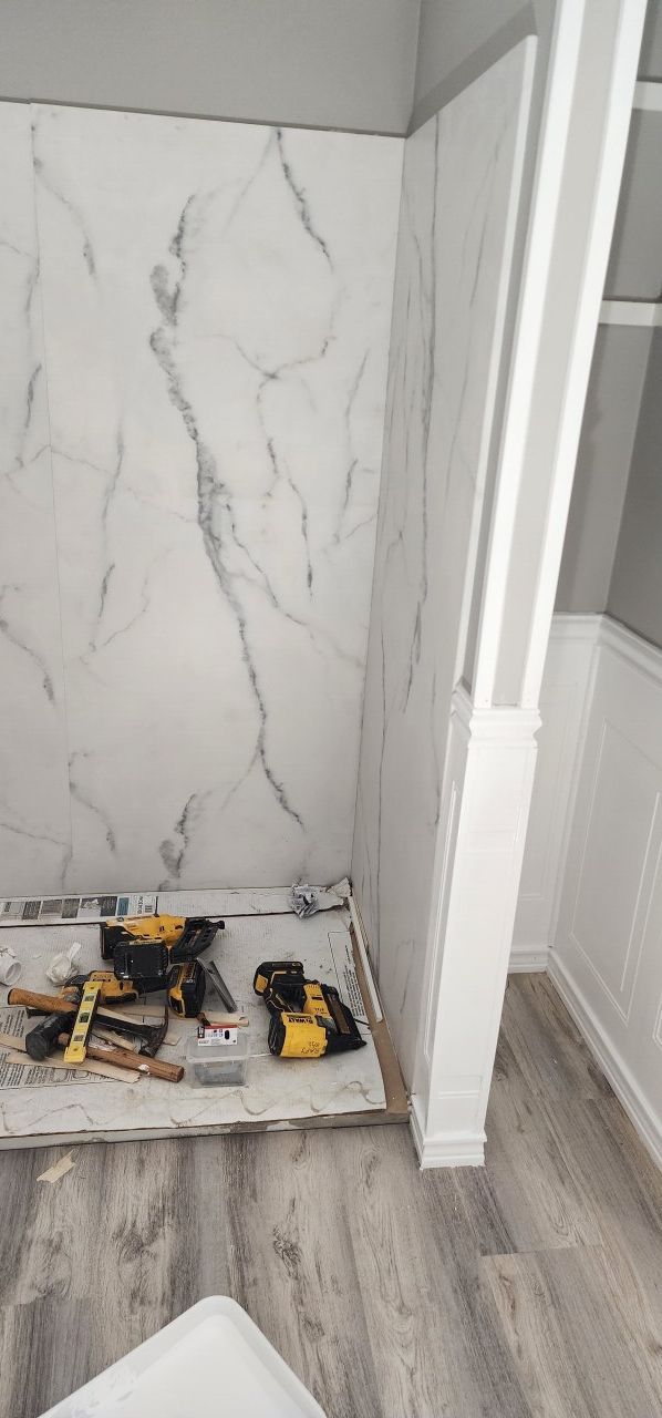 A room with a marble wall and wooden floor is being remodeled.