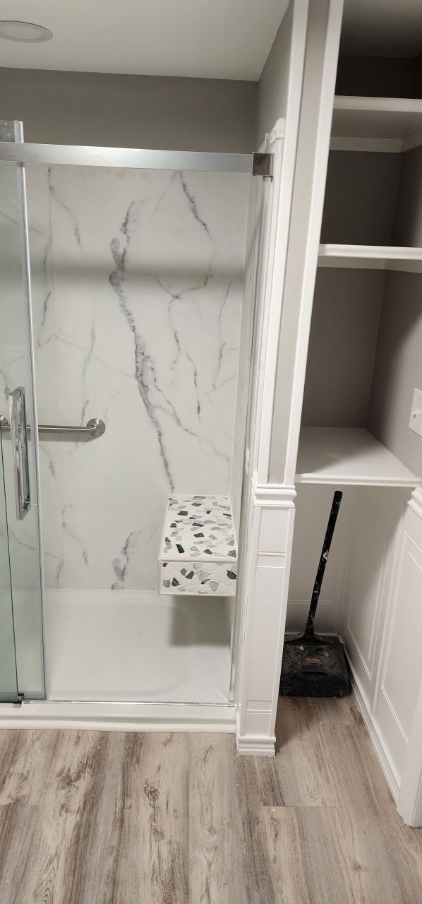 A bathroom with a walk in shower and a bench.