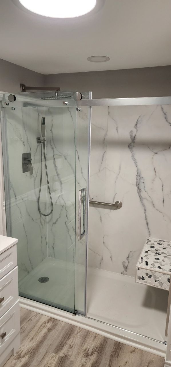 A bathroom with a walk in shower and marble walls.