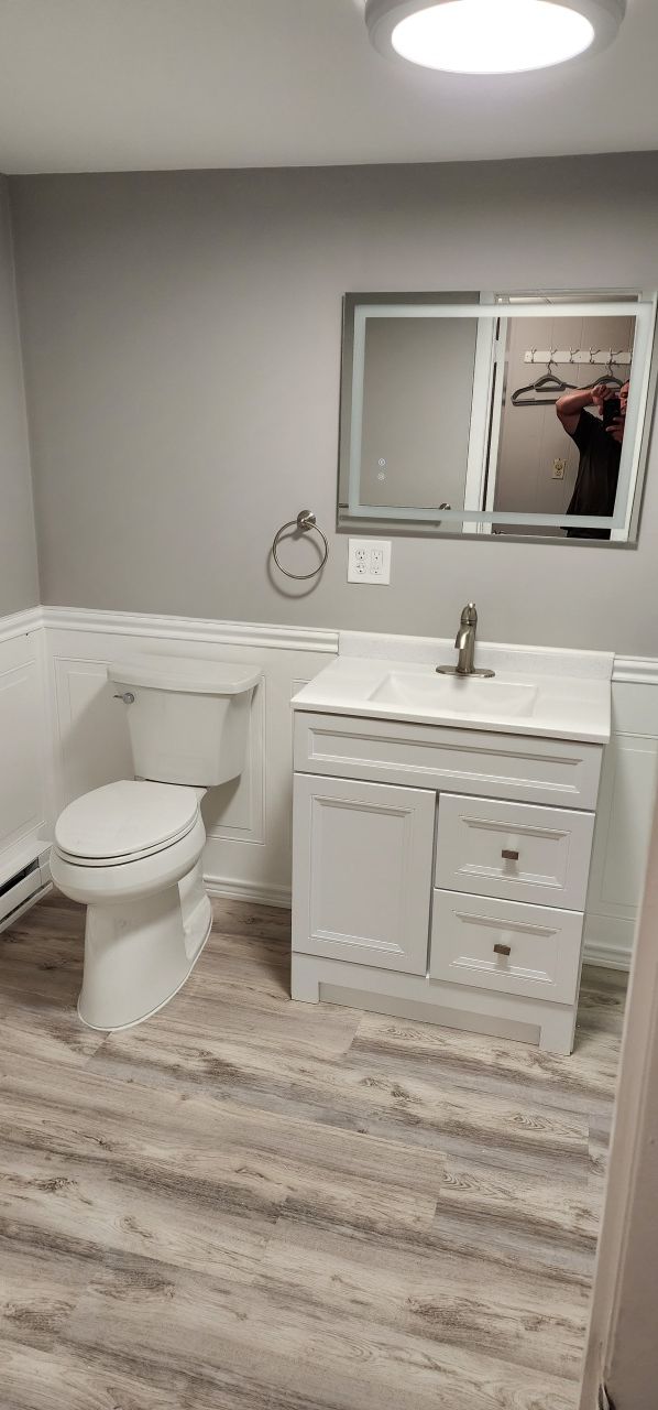 A bathroom with a toilet , sink and mirror.