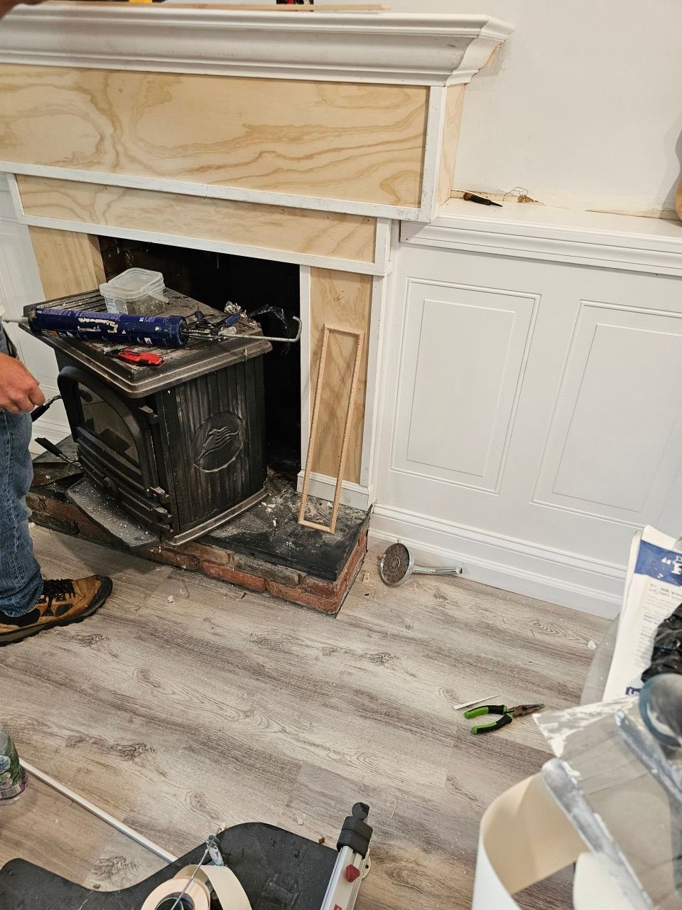 A man is working on a fireplace in a living room.