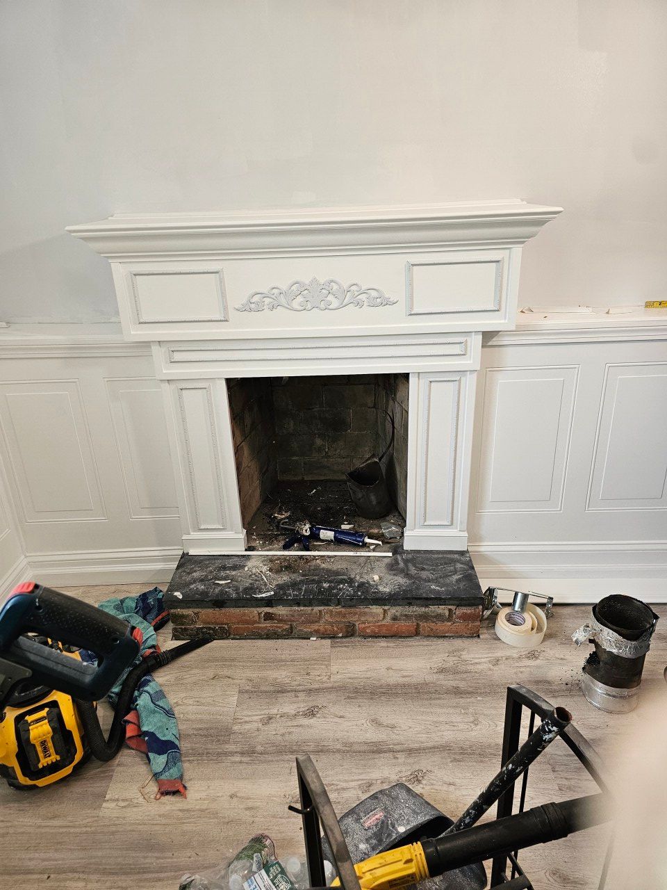 A fireplace in a living room with a vacuum cleaner in front of it.