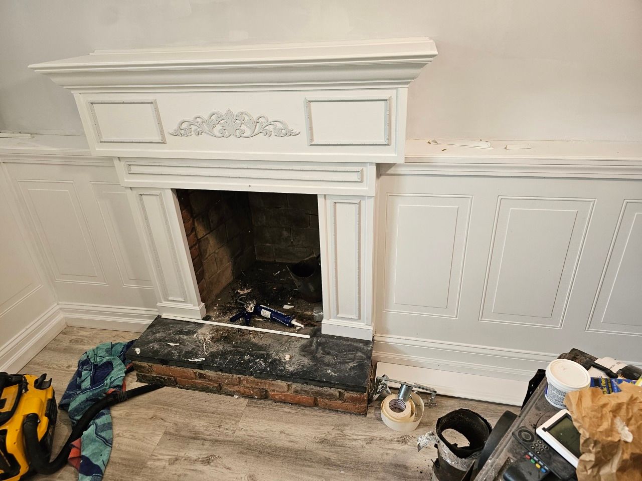 A fireplace is being painted in a living room.