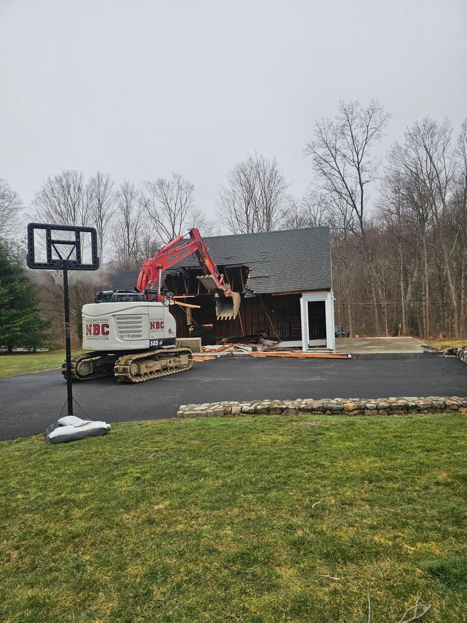 A house is being demolished and a basketball hoop is in the foreground.
